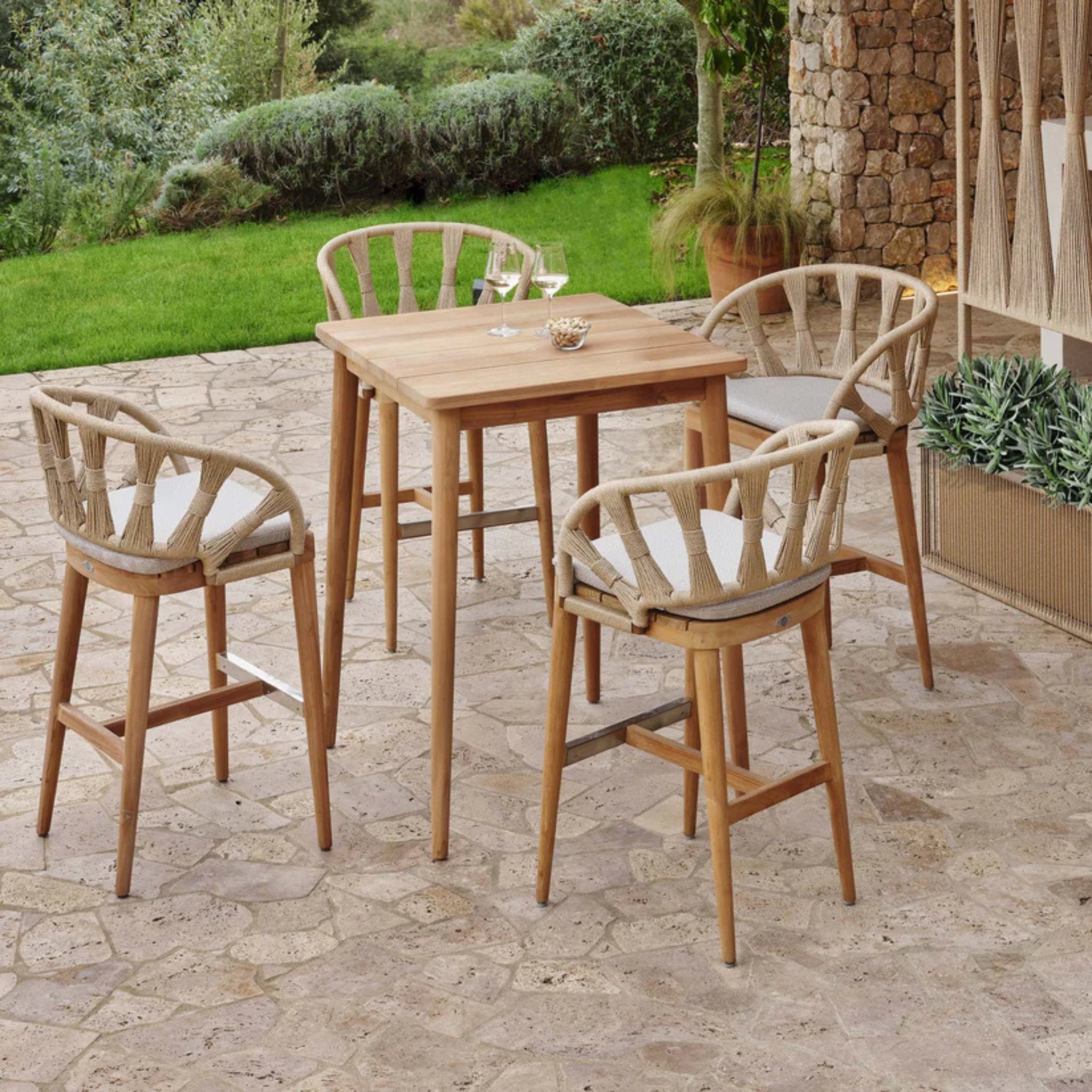 Skyline Design Krabi 5-piece outdoor dining set with teak pub table and four matching barstools on a patio.