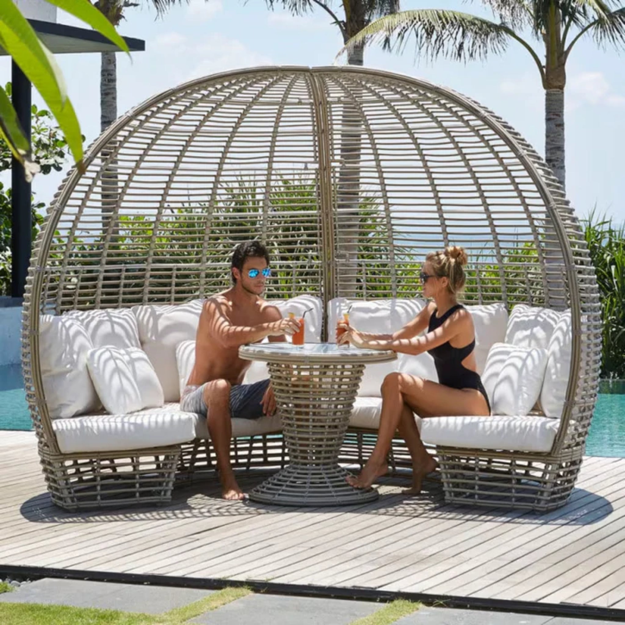 Skyline Design Nexus outdoor daybed with woven fiber in mushroom finish, featuring a built-in table for patio lounging.