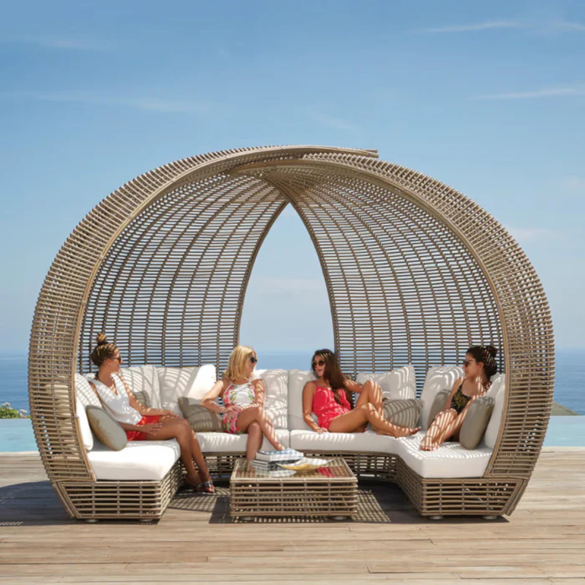 Skyline Design Sparta outdoor daybed with woven fiber frame in mushroom finish, featuring plush cushions and a modern patio design.