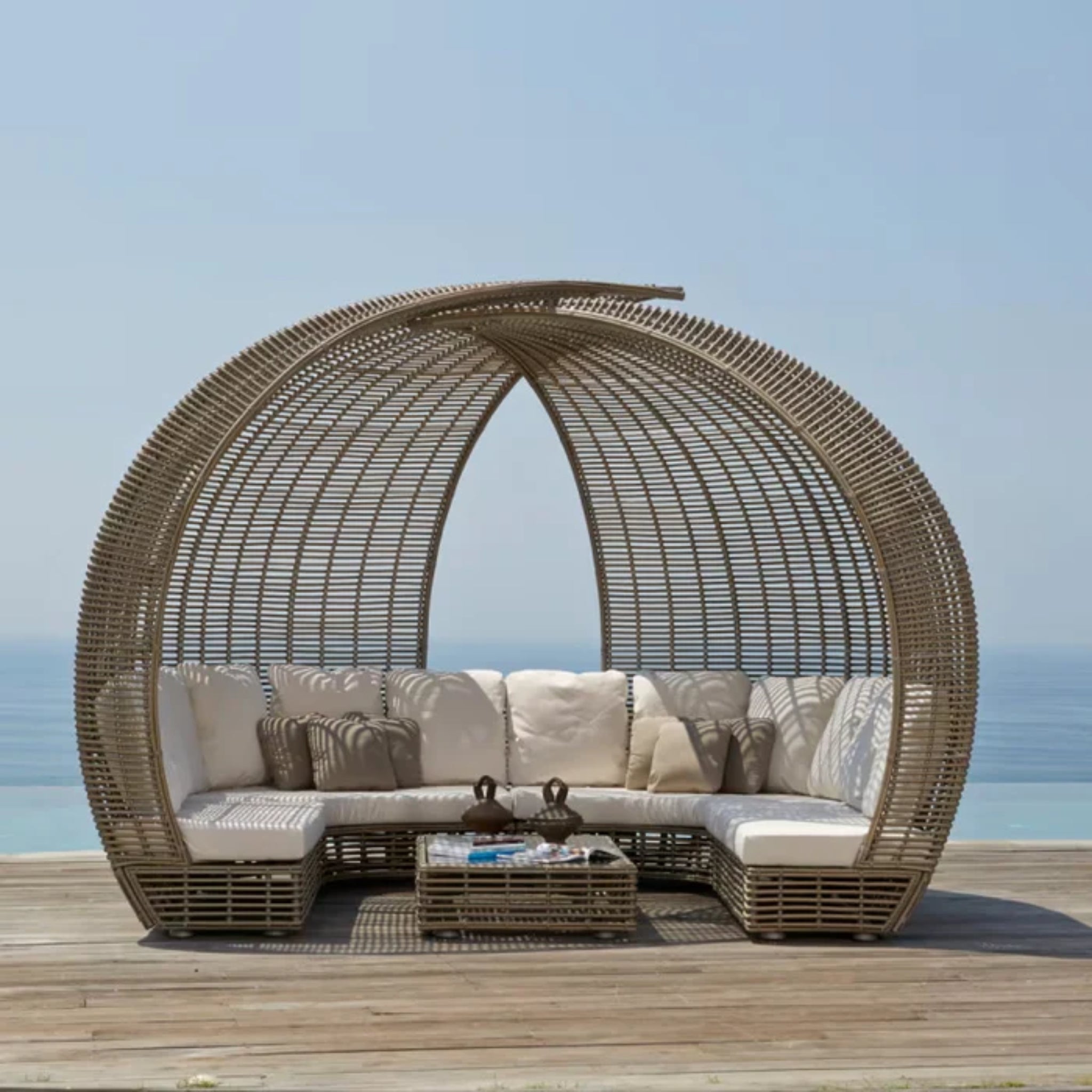 Skyline Design Sparta outdoor daybed with woven fiber frame in mushroom finish, featuring plush cushions and a stylish patio design.