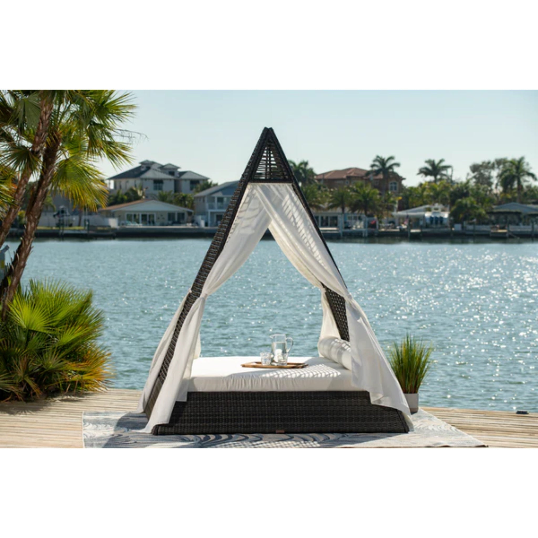Panama Jack Outdoor Helios luxury wicker outdoor daybed with plush cushions on a patio for relaxing outdoor lounging.